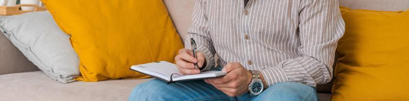 An image concentrated young bearded man sitting in notes on couch at home photo