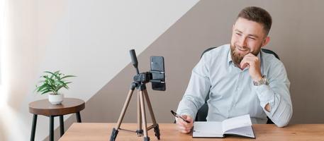 Young bearded man with smartphone and timetable notepad. Close-up business photo