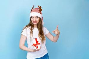 Cheerful young santa woman with horns received a christmas present in a white photo