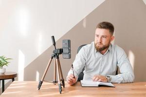 Young bearded businessman working in office sitting at table using smartphone photo