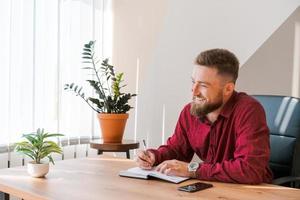 Portrait handsome smiling man with beard, working in office on some project, he photo