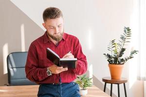Budget planning. Pensive bearded man writing in a notebook while sitting photo