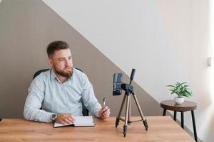 Young bearded businessman working in office sitting at table using smartphone photo
