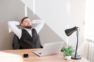 Handsome businessman is working with laptop in office, in business clothes photo