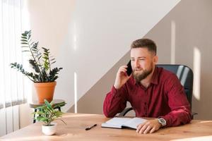 Business bearded man is talking on phone and plans to meet daily and write photo