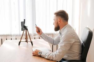 Young bearded man with smartphone and timetable notepad. Close-up business photo