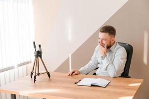 Young bearded businessman working in office sitting at table using smartphone photo