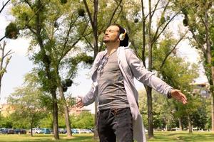 Smiling man enjoying in sunlight with arms outstretched at the park. photo