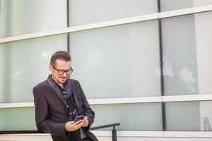 Smiling businessman reading text message on mobile phone. photo