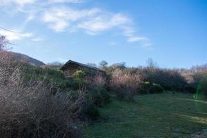 log cabin in the middle of the mountains with blue sky photo