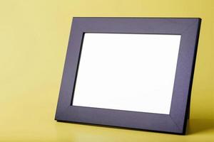 Black photo frame with free space on a yellow background.