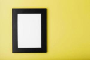 marco de fotos negro con espacio libre sobre un fondo amarillo.