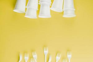 Disposable plastic tableware on a yellow background with free space. photo