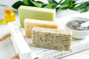 Beautiful Natural soap bars and ingredients on white tray background with clas, essential oil and exfoliation particles. Handmade organic soap concept photo