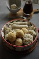 A bowl full of various shape fish cake with sour sauce on the background. photo