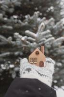 un modelo de una casa de madera ecológica en las manos sobre un fondo de invierno. foto