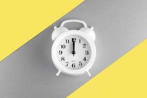 reloj despertador sobre fondo amarillo iluminador y gris definitivo en el espacio de copia. estilo de color del año 2021 foto