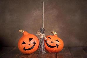 Two Halloween pumpkins and a witch's broom on a dark background. photo