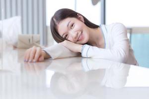 Portrait of restless beautiful young female is feeling tired and laying on desk. Woman model sit in the glassed room as business room. photo