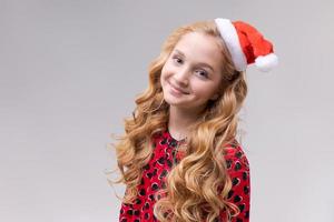 Christmas girl. Beautiful teen model in santa hat isolated on background photo