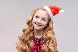 Christmas girl. Beautiful teen model in santa hat isolated on background photo