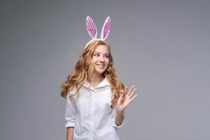 Young beautiful woman in cute easter bunny ears makes a normal gesture, plays photo