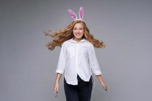 Girl in rabbit ears on her head against backdrop studio. Cheerful suffering photo