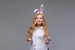 Young beautiful woman in cute easter bunny ears makes a normal gesture, plays photo