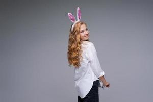 Girl in rabbit ears on her head against backdrop studio. Cheerful suffering photo