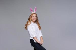 Girl in rabbit ears on her head against backdrop studio. Cheerful suffering photo