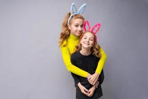Close-up portrait two cheerful pretty young girls with bunny ears in yellow photo