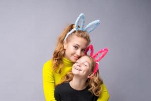 Close-up portrait two cheerful pretty young girls with bunny ears in yellow photo