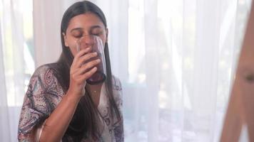 joven hermosa mujer en túnica bebe un vaso de agua frente al espejo video