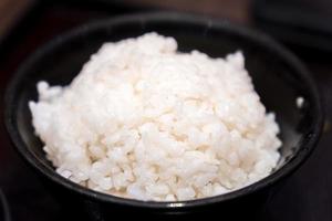 Japanese cooked rice in a black porcelain cup photo