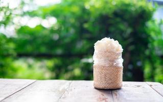 Wooden bamboo traditional style box with Thai sticky rice on wooden table and blurred nature background photo