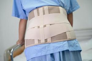 Asian lady patient wearing back pain support belt for orthopedic lumbar with walker. photo