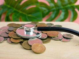 A stethoscope placed on a pile of money is a financial exam concept photo