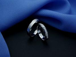 anillo de bodas de oro blanco. anillo de pareja con acabado brillante y apagado con fondo azul y negro foto