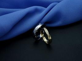 alianza de oro blanco y oro amarillo. anillo de pareja con acabado brillante y apagado con fondo azul y negro foto