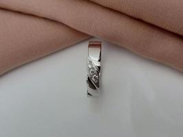 anillo de bodas de oro blanco. anillo simple con acabado brillante y apagado con fondo de tela marrón y base blanca foto