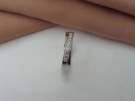 anillo de bodas de oro blanco. anillo simple con acabado brillante y apagado con fondo de tela marrón y base blanca foto