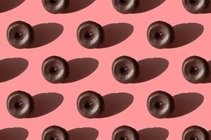 Food seamless pattern of tasty chocolate glazed donuts with a shadows on a pink background photo