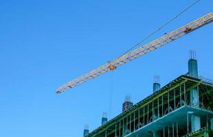 Construction crane against the blue sky. The real estate industry. A crane uses lifting equipment at a construction site. photo