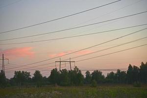 hermosa línea de transmisión de hierro de alto voltaje por la noche en el cielo del atardecer. noche de paisaje y cables y líneas eléctricas. foto