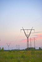 hermosa línea de transmisión de hierro de alto voltaje por la noche en el cielo del atardecer. noche de paisaje y cables y líneas eléctricas. foto