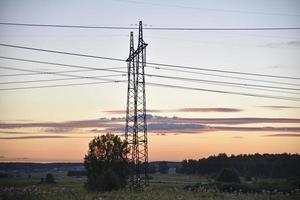 Beautiful high-voltage iron transmission line in the evening in the sunset sky. Landscape evening and wires and power lines. photo