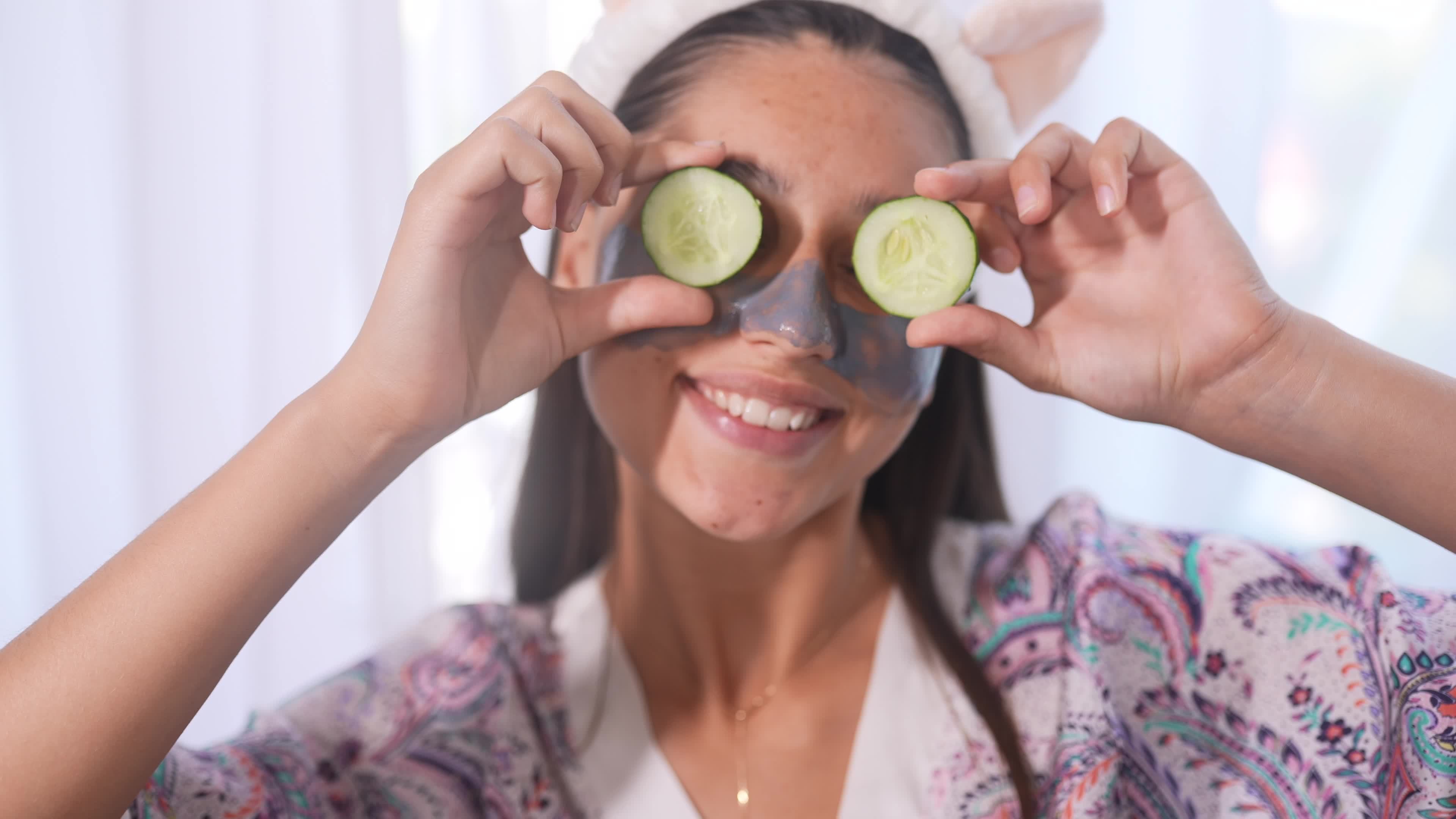 Young beautiful woman uses cucumber slices on eyes during skin care