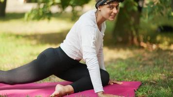 mulher faz exercícios de ioga com outras pessoas em um parque video