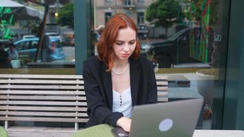 une femme d'affaires aux cheveux rouges travaillant à l'extérieur video