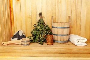 Interior details Finnish sauna steam room with traditional sauna accessories basin birch broom scoop felt hat towel. Traditional old Russian bathhouse SPA Concept. Relax country village bath concept. photo